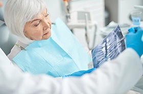 Dentist and patient looking at X-Ray, discussing dental implant treatment