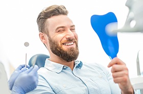 Dental implant patient using mirror to admire his new restorations