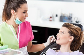 Woman in dental chair talking to team member