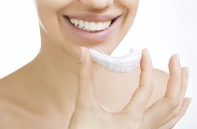 Woman placing at-home teeth whitening tray