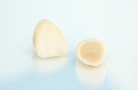 Two dental crowns on light-colored reflective surface