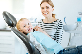 Mother and young daughter smiling in dental office