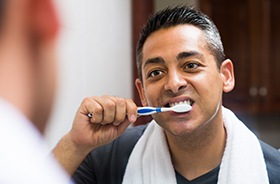 Man brushing his teeth to take care of his dental implants in Hamden
