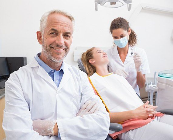 Dentist dental team member and patient in exam room