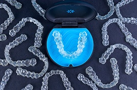 Invisalign aligner in storage case, surrounded by clear aligners