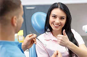 Woman in dental chair giving thumbs up