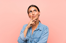 Portrait of thinking woman against pink background