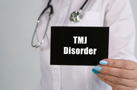 Doctor holding sign that says “TMJ disorder”