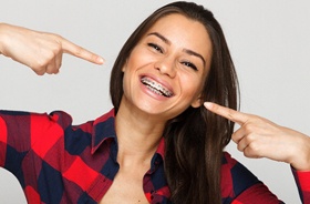 Happy woman pointing at her traditional braces in Hamden