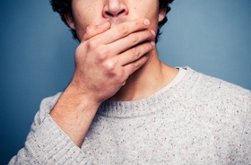 Man covering mouth to hide embarrassing orthodontic problem