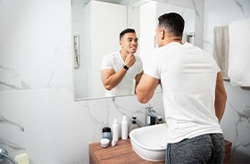 Young man looking at his smile in bathroom mirror