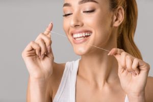 woman using floss to protect dental hygiene during quarantine
