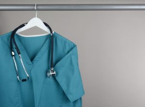 freshly cleaned scrubs and stethoscope hanging in dental office closet