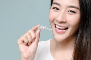 Woman holding clear aligner, fixing TMJ with Invisalign