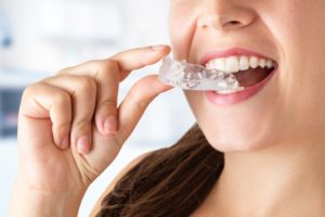 Woman holding mouthguard for bruxism and dental implants