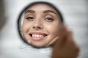 Woman admiring her straight teeth after braces removal in Hamden