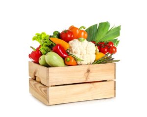 Box of raw vegetables against white background