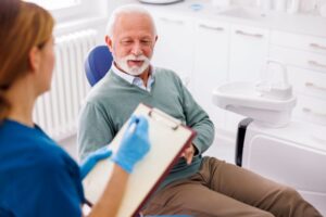 Dental team member taking notes during dental implant consultation