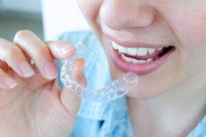 Person holding Invisalign aligner close to her mouth 
