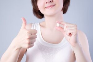 Woman making thumbs-up gesture while holding her extracted tooth