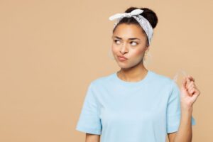 Young woman holding Invisalign aligner, wearing thoughtful expression