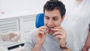Dental patient placing Invisalign aligner in his mouth