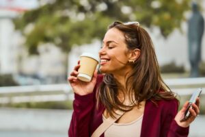 Happy professional woman holding a disposable coffee cup 