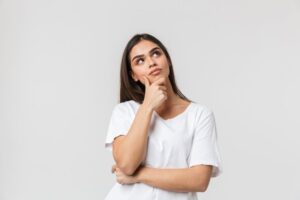 Woman in white t-shirt wearing thoughtful expression
